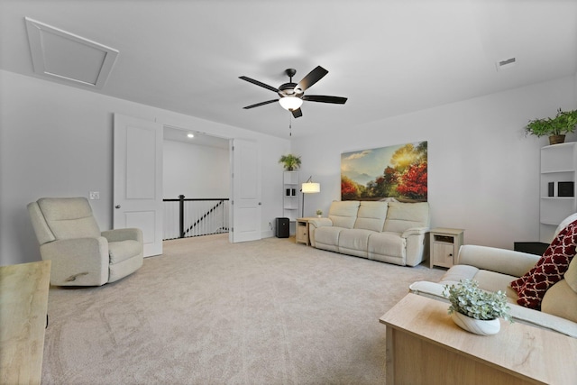 living room featuring carpet flooring, a ceiling fan, and attic access