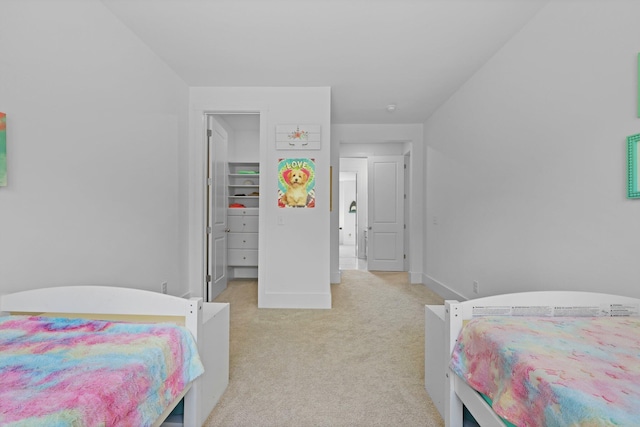 bedroom featuring light carpet, baseboards, and a walk in closet