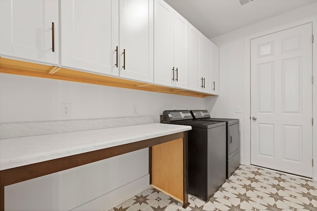 laundry room featuring separate washer and dryer, cabinet space, and light floors