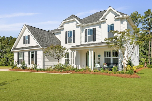 traditional-style house featuring covered porch, a front lawn, and roof with shingles