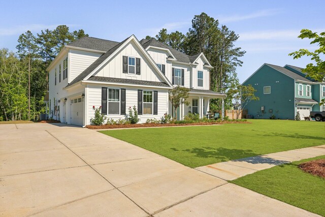 craftsman inspired home featuring board and batten siding, concrete driveway, a garage, a front yard, and a shingled roof