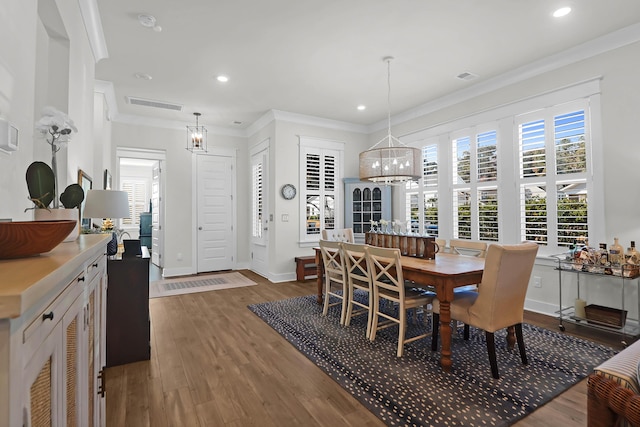 dining space with an inviting chandelier, ornamental molding, and dark hardwood / wood-style flooring