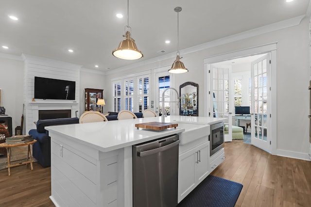 kitchen with pendant lighting, sink, stainless steel appliances, an island with sink, and white cabinets