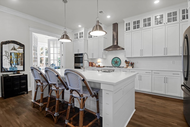 kitchen featuring a kitchen island with sink, white cabinets, and wall chimney exhaust hood