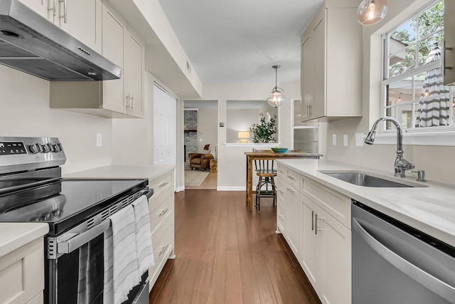 1433 Oaklanding Rd, Mount Pleasant, SC 29464 - kitchen with stainless steel appliances, under cabinet range hood, light countertops, dark wood-style floors, and hanging light fixtures