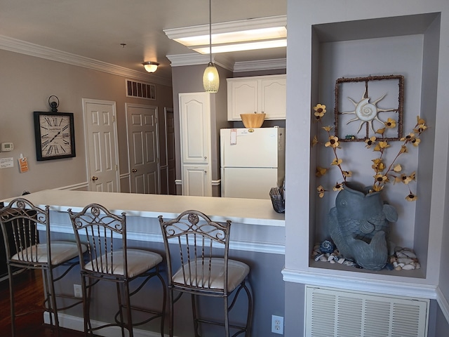 kitchen with a breakfast bar area, decorative light fixtures, white refrigerator, white cabinetry, and dark hardwood / wood-style floors