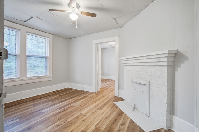 unfurnished living room featuring a paneled ceiling, ceiling fan, and light hardwood / wood-style flooring