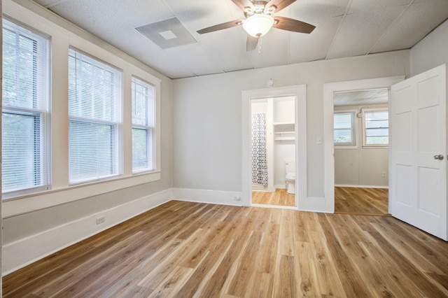 unfurnished bedroom with ensuite bath, ceiling fan, a spacious closet, light hardwood / wood-style flooring, and a closet