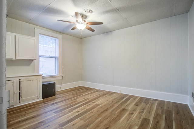 spare room featuring a paneled ceiling, ceiling fan, and light hardwood / wood-style flooring