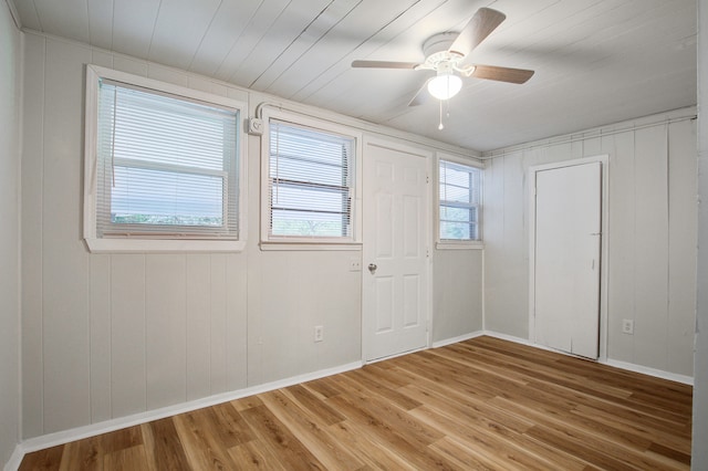 unfurnished room with hardwood / wood-style floors, ceiling fan, and wood walls