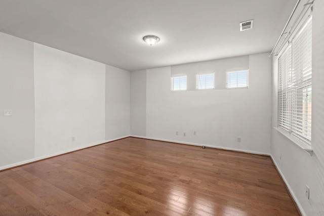 empty room featuring visible vents, baseboards, and wood finished floors