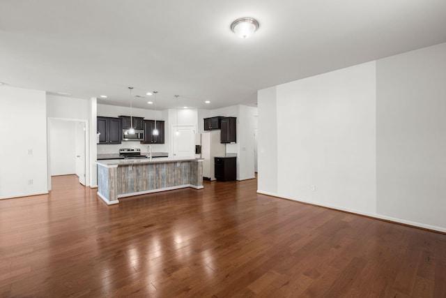 kitchen with a center island with sink, dark wood-style flooring, stainless steel appliances, light countertops, and open floor plan