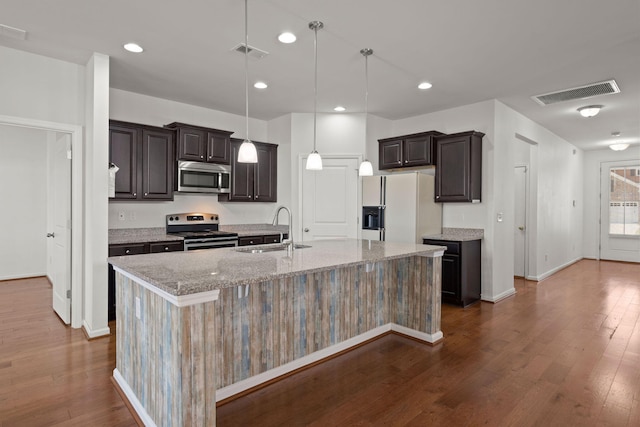 kitchen with a sink, visible vents, appliances with stainless steel finishes, and a center island with sink