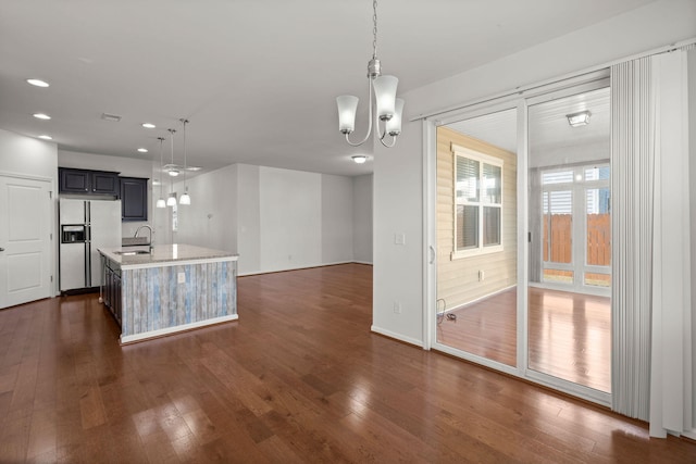 kitchen featuring dark wood finished floors, light countertops, white refrigerator with ice dispenser, and a sink