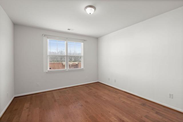 unfurnished room featuring visible vents, baseboards, and wood finished floors