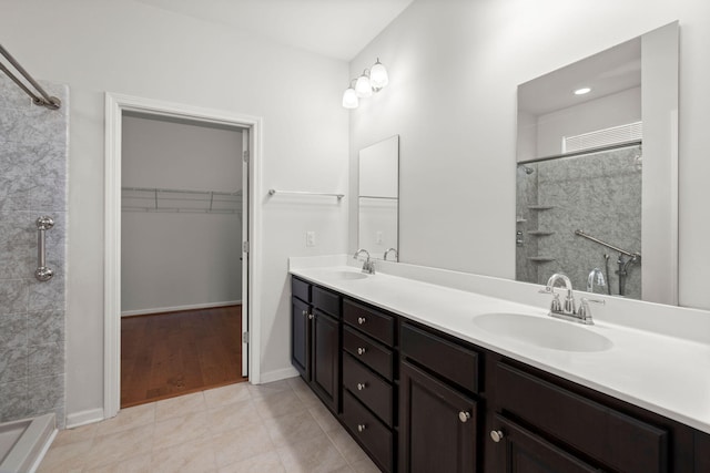 bathroom with double vanity, tiled shower, and a sink