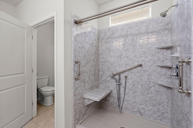 full bathroom with tiled shower, toilet, and tile patterned flooring