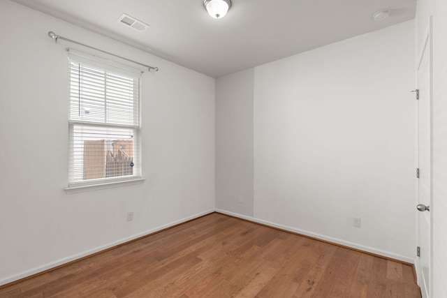 spare room with visible vents, baseboards, and wood finished floors