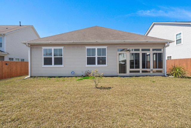 rear view of property featuring fence private yard, roof with shingles, a yard, and a sunroom