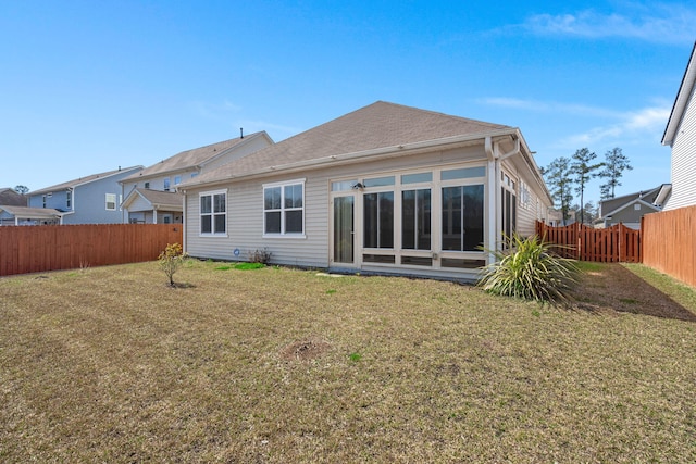 rear view of house featuring a yard and a fenced backyard