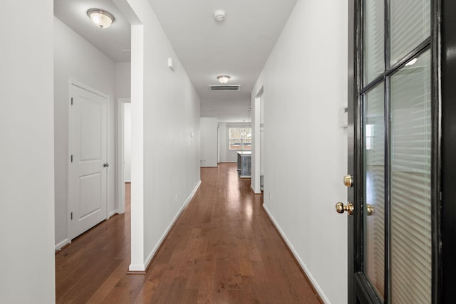 corridor featuring visible vents, baseboards, and wood finished floors