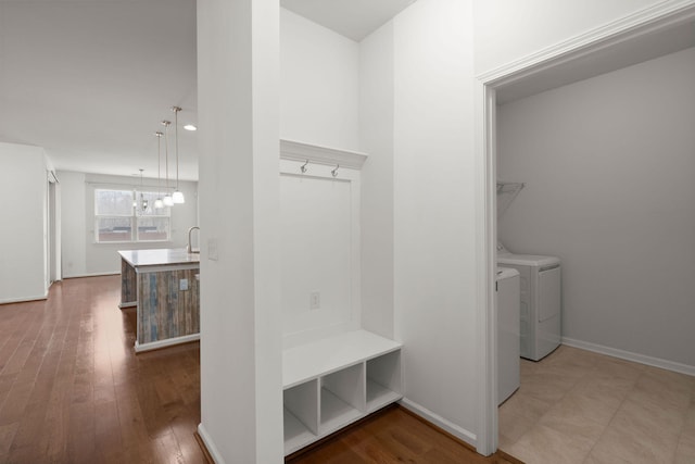 mudroom with a sink, baseboards, wood-type flooring, and washing machine and dryer