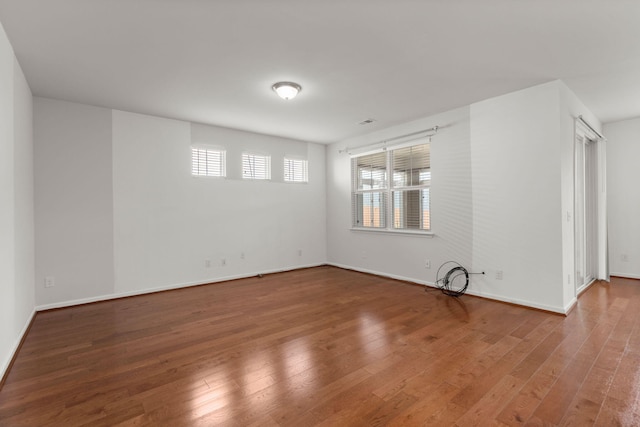 empty room with hardwood / wood-style floors and baseboards