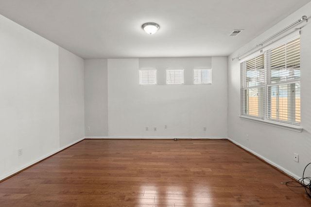 spare room with visible vents, wood finished floors, and baseboards