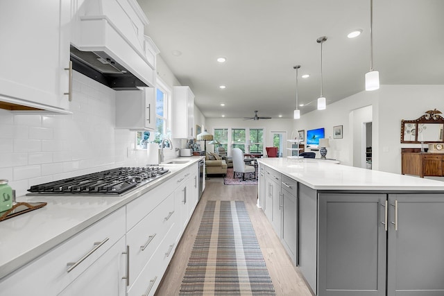 kitchen with a center island, stainless steel gas cooktop, gray cabinetry, open floor plan, and white cabinets