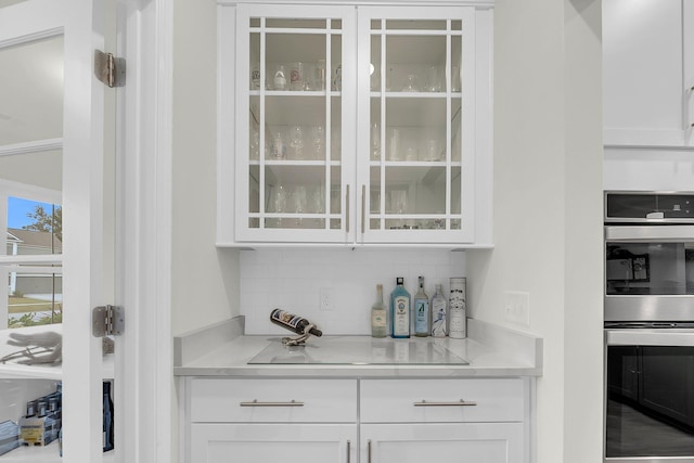 bar featuring stainless steel double oven and backsplash