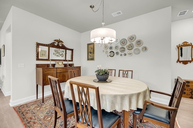 dining area featuring light wood finished floors, visible vents, and baseboards