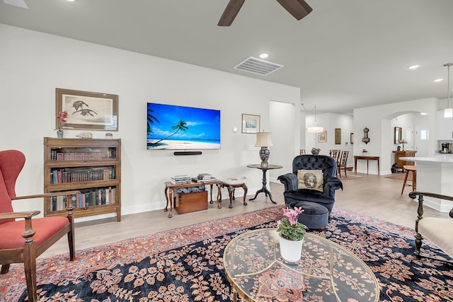 living area with arched walkways, recessed lighting, visible vents, a ceiling fan, and light wood finished floors