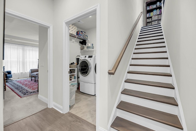 clothes washing area with laundry area, separate washer and dryer, baseboards, and wood finished floors