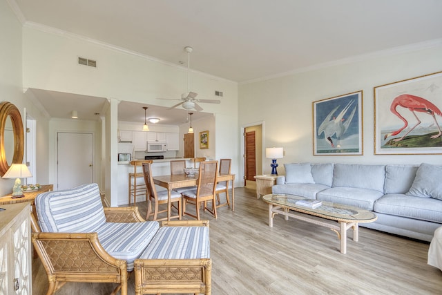 living room with light hardwood / wood-style floors, ornamental molding, and ceiling fan