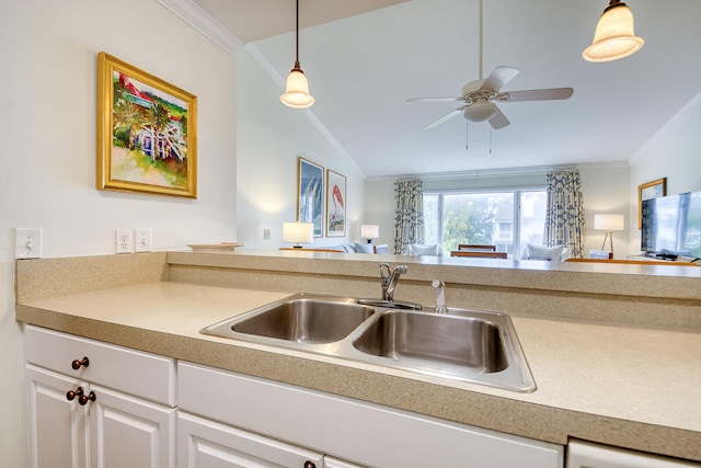 kitchen with white cabinetry, lofted ceiling, crown molding, pendant lighting, and sink