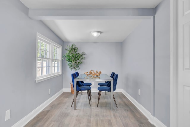 dining room with beamed ceiling and light hardwood / wood-style flooring