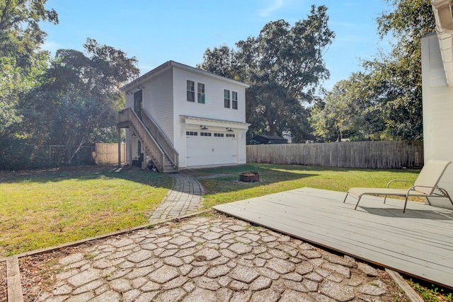 exterior space with a garage, a deck, an outdoor fire pit, and a yard