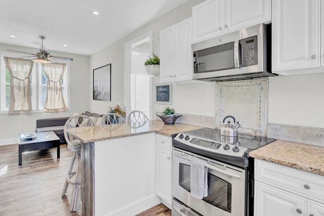 kitchen featuring ceiling fan, kitchen peninsula, stainless steel appliances, and white cabinetry