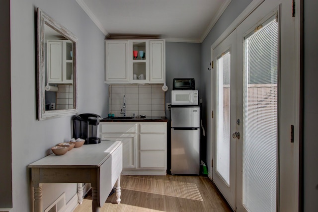 kitchen featuring sink, backsplash, white cabinets, and stainless steel refrigerator