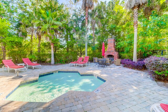 view of pool with an outdoor brick fireplace and a patio area