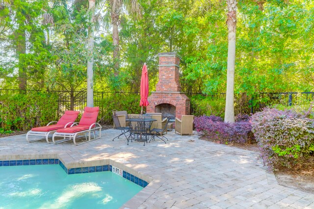 view of swimming pool featuring a patio and an outdoor brick fireplace