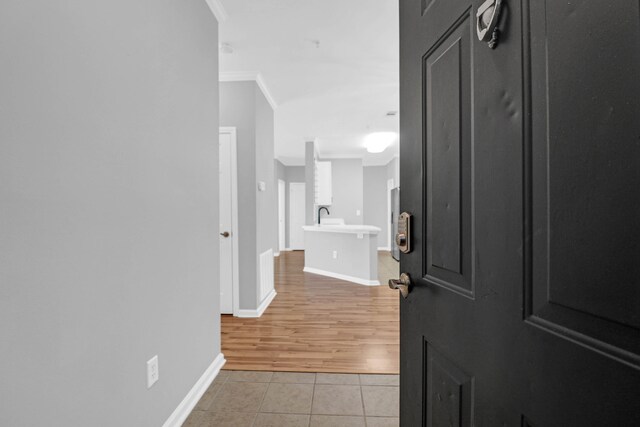 hall with ornamental molding, sink, and light wood-type flooring