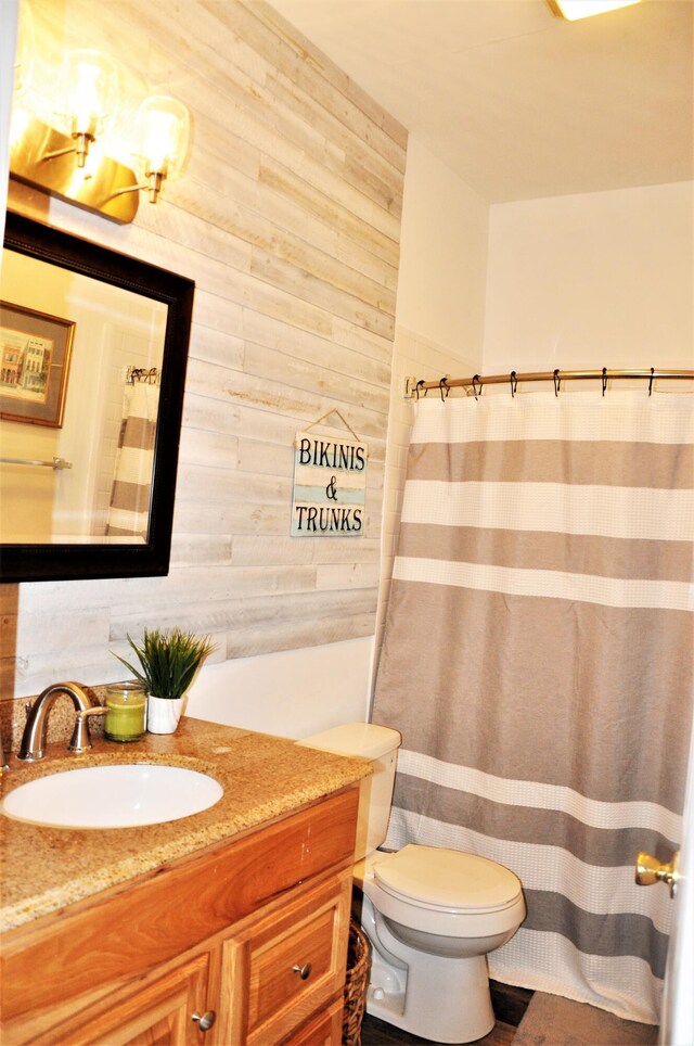 bathroom with vanity, toilet, and wood walls