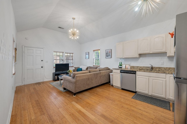 living room featuring a chandelier, sink, high vaulted ceiling, and light hardwood / wood-style floors