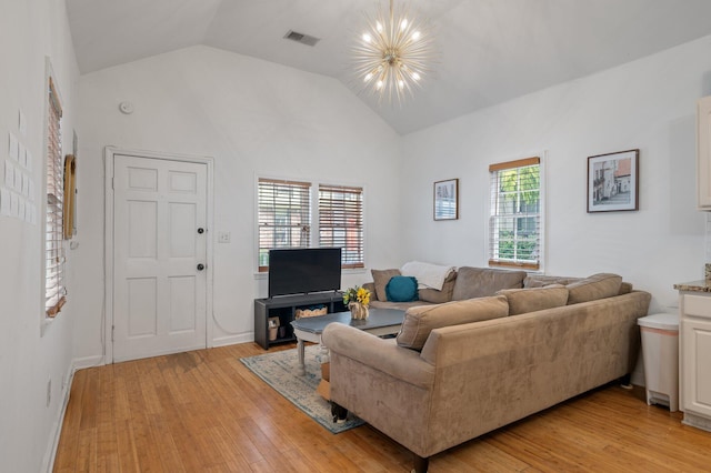 living room with light hardwood / wood-style flooring, high vaulted ceiling, and an inviting chandelier