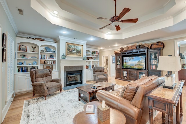 101 Firestone Ct, Summerville, SC 29483 - living area with crown molding, a ceiling fan, a raised ceiling, a tiled fireplace, and light wood-style flooring
