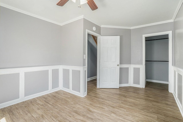 unfurnished bedroom with ornamental molding, light wood-type flooring, wainscoting, and ceiling fan