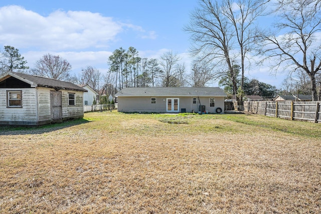 back of house with a fenced backyard, a yard, and an outdoor structure