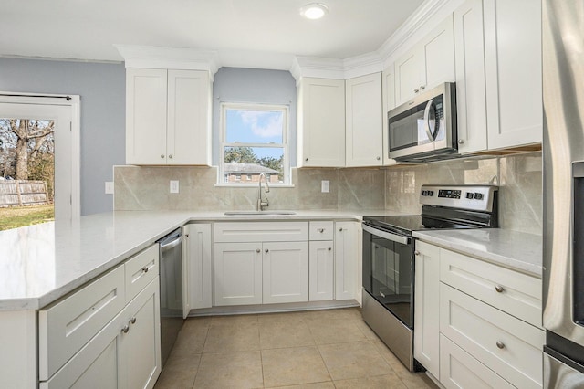 kitchen featuring light tile patterned floors, appliances with stainless steel finishes, white cabinetry, a sink, and a peninsula