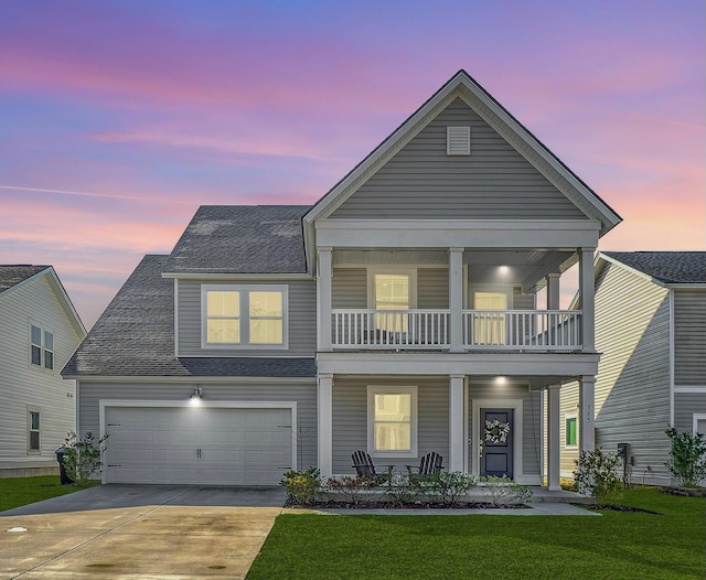 view of front of house with a balcony, covered porch, a shingled roof, concrete driveway, and a front lawn